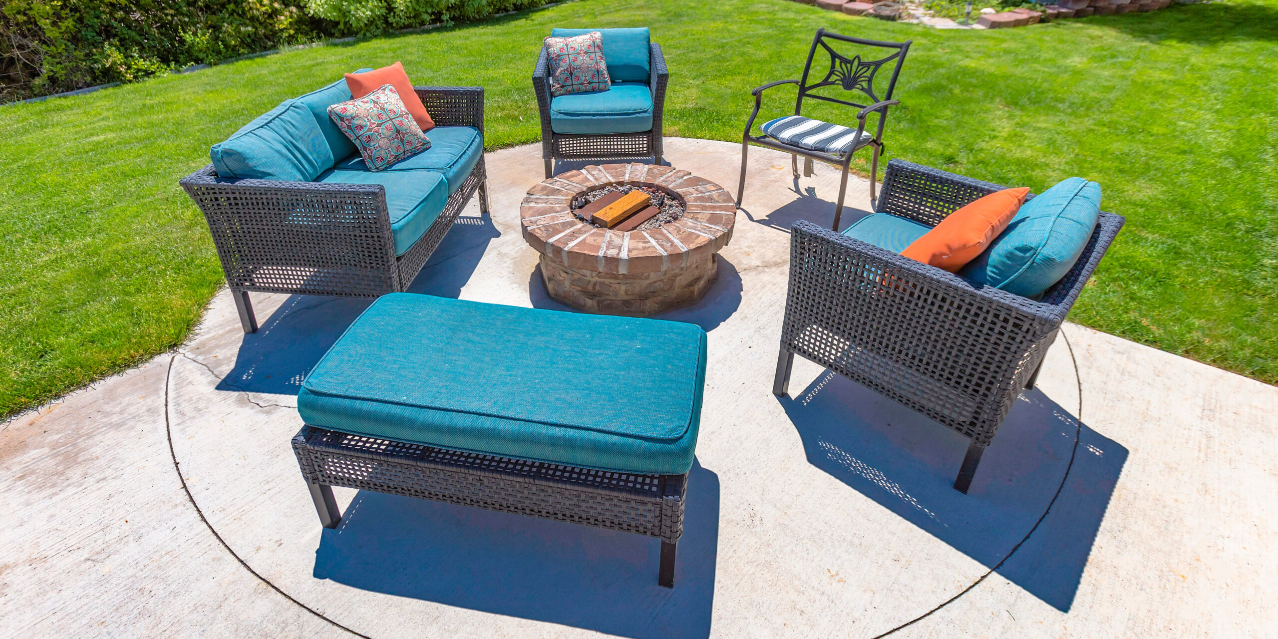 Circular fire pit and chairs on a sunny backyard